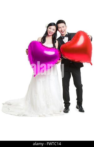 Happy Bride and Groom holding heart-shaped balloons Banque D'Images