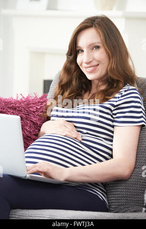 Pregnant Woman Using Laptop Computer At Home Banque D'Images