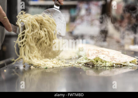 La cuisson de la pizza japonaise okonomiyaki Banque D'Images