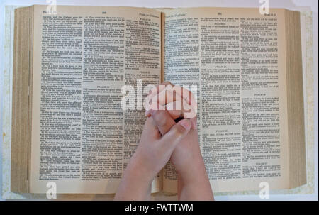 Un enfant priant sur une Bible ouverte Banque D'Images