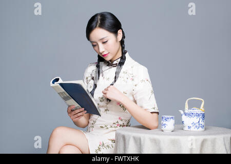 Young Beautiful woman reading book cheongsam traditionnel Banque D'Images