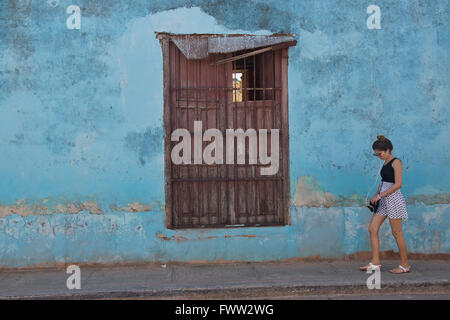 Une femme passe devant un mur de différentes couleurs et textures de la vieille ville de Trinidad de Cuba. Banque D'Images