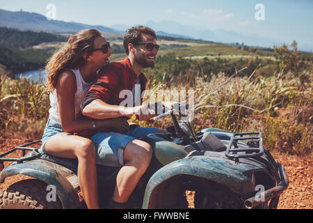 L'homme et la femme s'amusant sur une aventure hors route. Couple sur un quad en pleine campagne sur une journée d'été. Banque D'Images