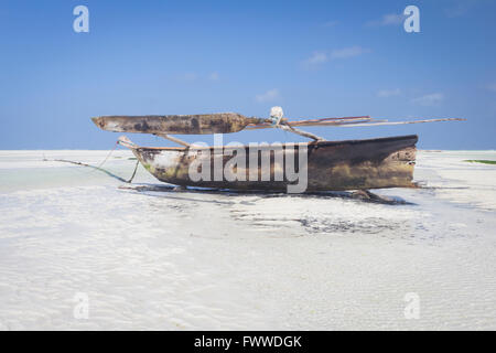 Bateau en bois en Dhow couché au sec à marée basse sur une plage de l'Océan Indien près de Zanzibar, Tanzanie Banque D'Images