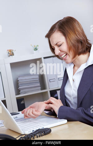 Femme avec ordinateur de bureau avec de l'arthrite dans ses main poignet Banque D'Images