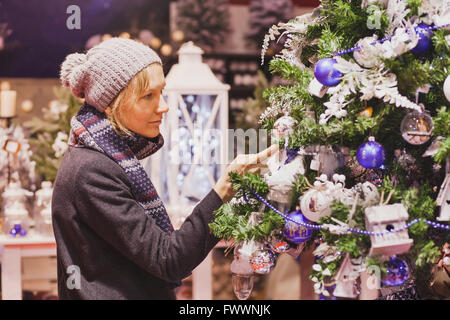 Nos gens au marché de Noël, le choix de la femme dans la boutique décoration de fête Banque D'Images
