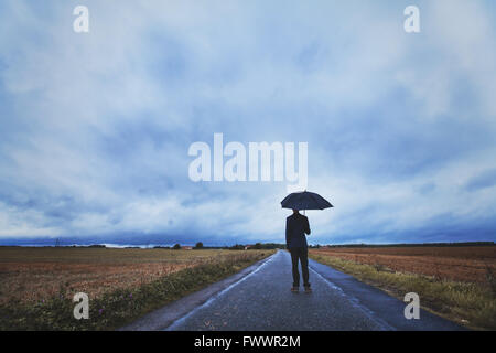 Concept de la psychologie, l'homme debout avec parasol sur la route, les peurs et la solitude Banque D'Images
