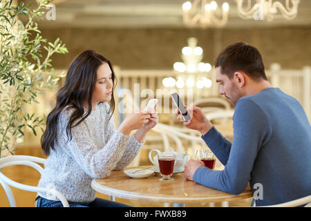 Couple avec les smartphones de boire du thé au café Banque D'Images