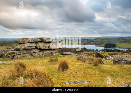 Moody dramatique ciel au-dessus de formations rocheuses sur Tregarrick Tor sur Bodmin Moor en Cornouailles avec Siblyback lac au loin Banque D'Images