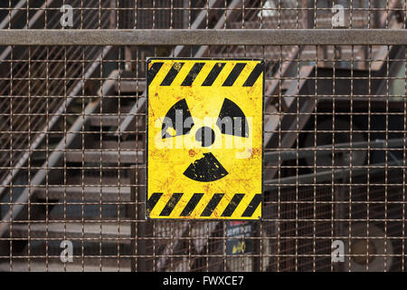 Radioactifs jaune warning sign on clôture rouillée Banque D'Images