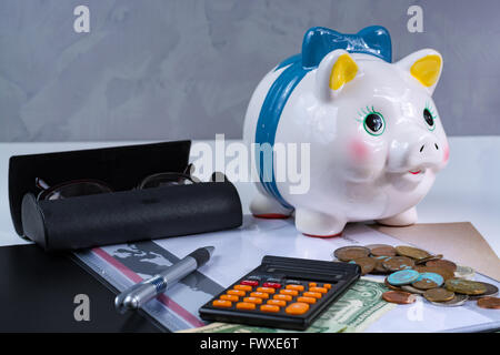 Tirelire et les accessoires, lunettes, calculatrice sur fond blanc Banque D'Images