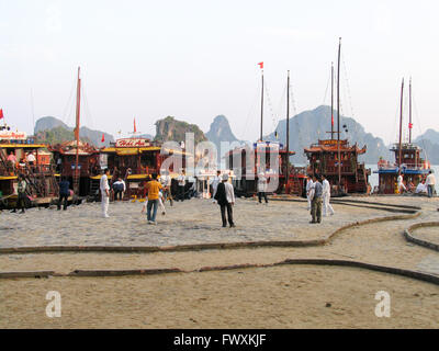 Junk six bateaux amarrés à l'île de Ti Top, Halong Bay, Vietnam, et d'un groupe de Vietnamiens hommes jouant un coup de volant. Banque D'Images