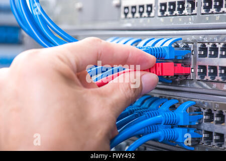 Homme travaillant dans network server room avec moyeu en fibre optique pour les communications numériques et internet Banque D'Images