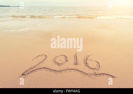 Année 2016 écrit à la main sur le sable blanc en face de la mer Banque D'Images