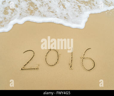 Année 2016 écrit à la main sur le sable blanc en face de la mer Banque D'Images