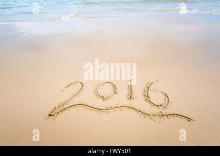 Année 2016 écrit à la main sur le sable blanc en face de la mer Banque D'Images