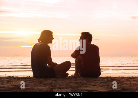 L'homme et la femme sur la plage au coucher du soleil, jeune couple parler près de la mer, l'amitié ou de rencontres concept Banque D'Images