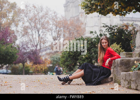 Belle femme en rouge, portrait of caucasian fashion jeune modèle aux cheveux longs assis tout seul, la psychologie concept Banque D'Images