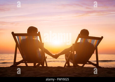 Contexte L'amour romantique, lune de miel, couple de détente sur la plage au coucher du soleil Banque D'Images