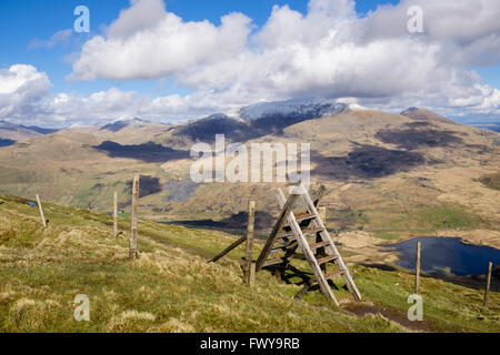 Bain stile sur chemin sur Mynydd Drws-y-coed sur Nantlle Ridge avec snowcapped Mount Snowdon en nuages dans le Snowdonia au Pays de Galles UK Banque D'Images