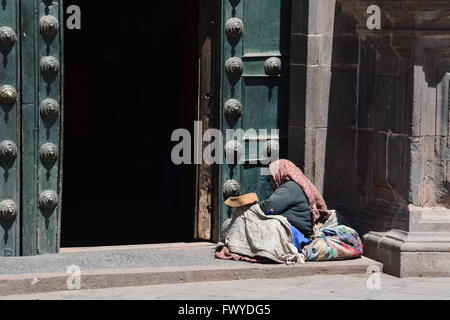 Une vieille femme pose devant les portes de l'église catholique de La Merced à Cusco au Pérou. Banque D'Images