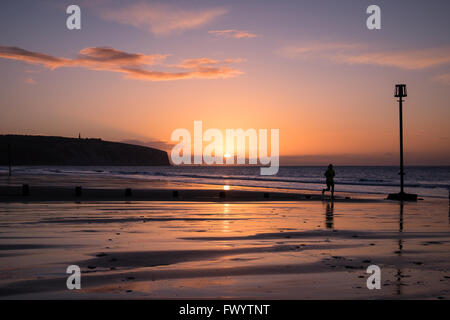 Un coureur et un chien au lever du soleil sur la plage de Sandown Banque D'Images