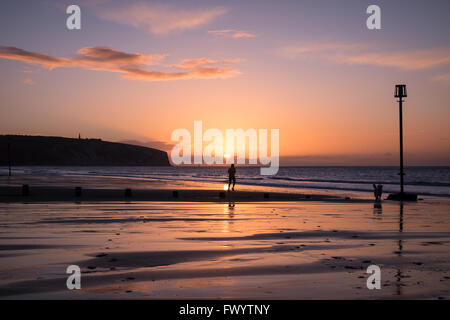 Un coureur et un chien au lever du soleil sur la plage de Sandown Banque D'Images