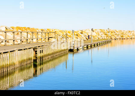 Jetée en bois juste à côté d'un grand quai de pierre. Le bois est un peu abîmé. L'eau est très calme sur cette journée de printemps sans vent dans le Banque D'Images