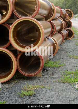 Pile de tuyaux d'eau marron sur la route. Banque D'Images