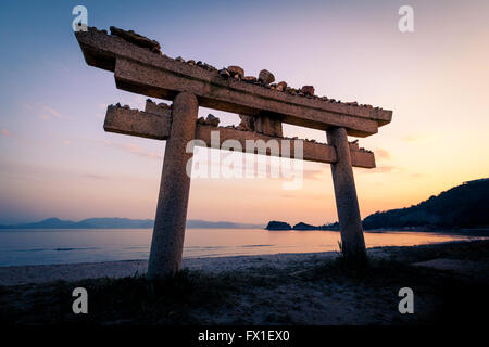 Torii de pierre sur la plage sur l'île de Naoshima, au Japon au coucher du soleil Banque D'Images