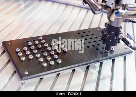 Un bras mécanique robotisée organise des petites billes de métal. La machine fait la démonstration de sa vitesse et la précision de l'exécution de tâches. Banque D'Images