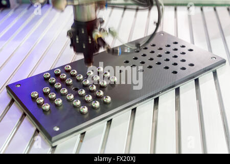 Un bras mécanique robotisée organise des petites billes de métal. La machine fait la démonstration de sa vitesse et la précision de l'exécution de tâches. Banque D'Images