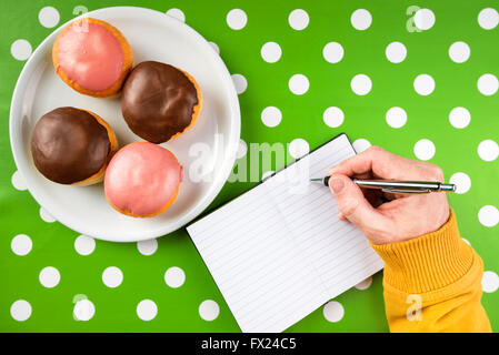 Recette pour écrire des délicieux beignets avec garniture sucrée, vue du dessus de la main des hommes dans l'ordinateur portable et de savoureux donuts avec Banque D'Images