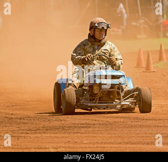 Homme avec bretelles casque & driving motofaucheuses émergeant de nuage de poussière rouge sur la voie dans le sport automobile australien inhabituelle Banque D'Images