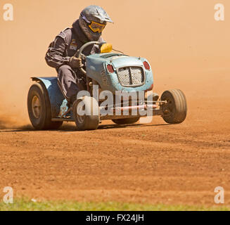 Homme avec bretelles casque & driving motofaucheuses émergeant de nuage de poussière rouge sur la voie dans le sport automobile australien inhabituelle Banque D'Images