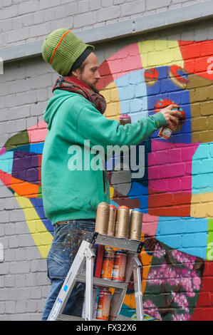 Un artiste de graffiti peinture par pulvérisation d'un morceau de travail colorés à Londres, Angleterre Royaume-Uni UK Banque D'Images