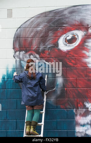 Jeune femme artiste graffiti graffiti peinture murale dans Londres, Angleterre Royaume-Uni UK Banque D'Images