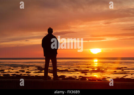 Southport, Merseyside, Royaume-Uni. 10 avril, 2016. Météo britannique. Coucher du soleil sur la mer d'Irlande comme vu de Southport promenade du front de mer donnant sur la grande plage de la station avec des reflets du soleil couchant. Il vient comme un temps plus chaud se déplace dans. Les températures sont mis à grimper et les choses seront glaciaire par le peuvent les jours fériés. Privé prévoient des températures pourrait atteindre 28 degrés et dire que cette année pourrait être le pays le plus chaud du printemps et l'été. Banque D'Images