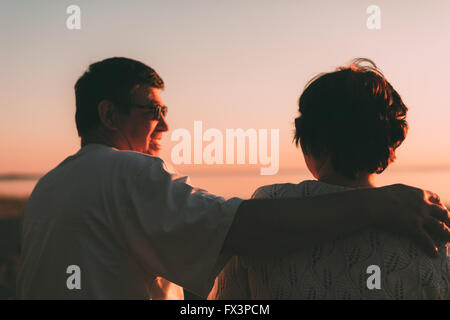 Vue arrière d'un couple marié une silhouette assise sur un banc. Banque D'Images