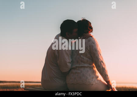 Vue arrière d'un couple marié une silhouette assise sur un banc. Banque D'Images