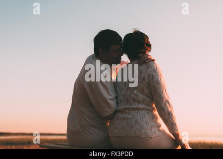 Vue arrière d'un couple marié une silhouette assise sur un banc. Banque D'Images