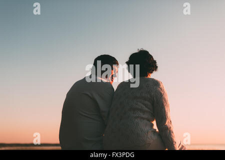 Vue arrière d'un couple marié une silhouette assise sur un banc. Banque D'Images