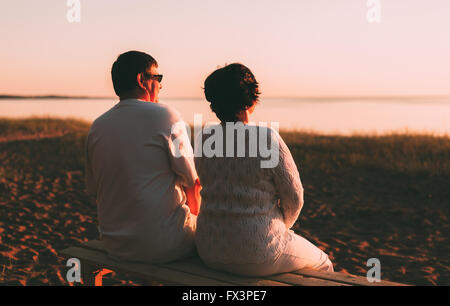 Vue arrière d'un couple marié une silhouette assise sur un banc. Banque D'Images