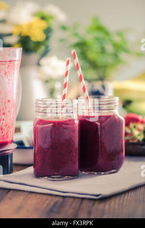 Smoothie aux petits fruits sur table en bois dans la cuisine ensoleillée, l'espace négatif pour le texte. Banque D'Images