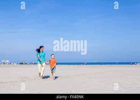 Maman et son fils s'exécutant sur la plage dans une journée d'été sur la mer Adriatique en Italie, Marina di Ravenna Banque D'Images