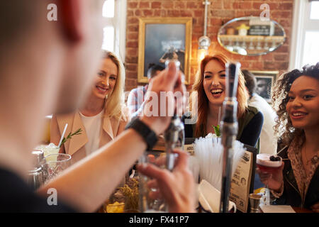 Barman servant les clients de sexe féminin dans un bar à cocktails Banque D'Images