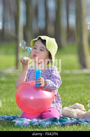 Petite fille est un souffle des bulles de savon dans la forêt Banque D'Images