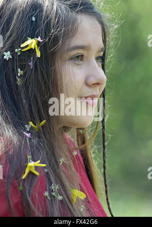 Belle fille avec des fleurs dans ses cheveux dans le printemps ! Banque D'Images