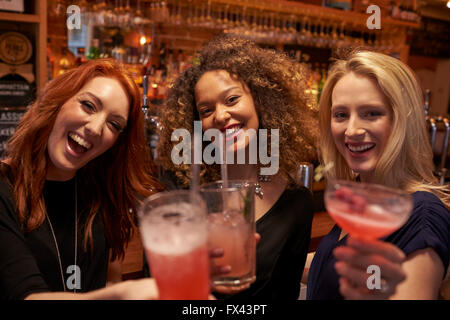 Réunion d'amis de sexe féminin pour prendre un verre en soirée au bar à cocktails Banque D'Images