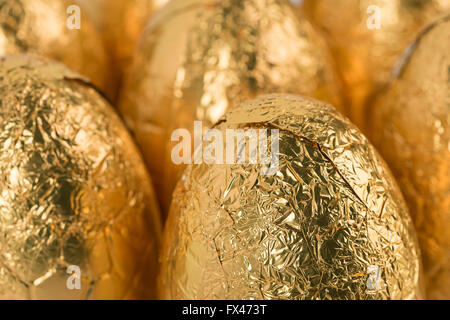 Plus d'indulgence dans les oeufs de Pâques en chocolat enveloppé dans la feuille d'or brillant dans les lignes prêt pour problème de santé surpoids chocoholic Banque D'Images